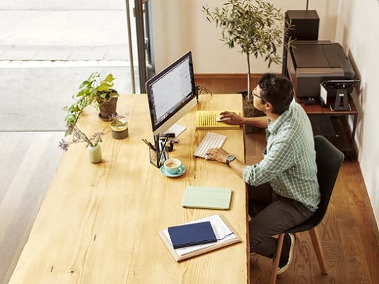 A man sits at his desk and looks at the GLS parcel receiving ptions on the GLS website on his iMac