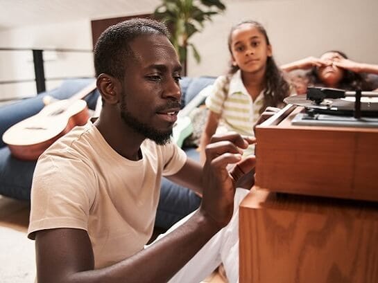 A man with his daughters listening to a record