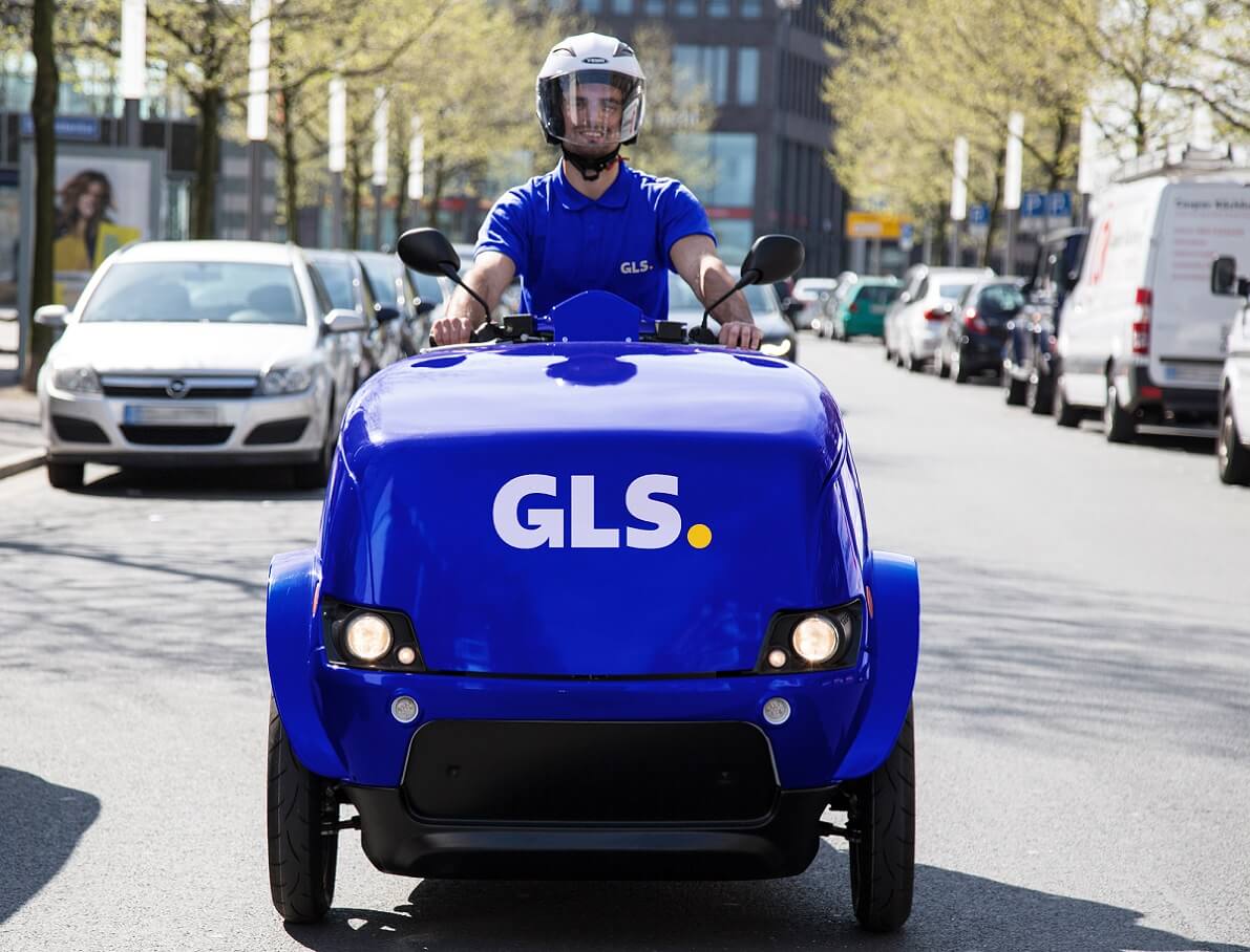 Ein GLS-Mitarbeiter, der einen Helm trägt und mit einem GLS-E-Bike ausliefert