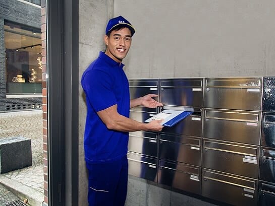A GLS employee delivers a flat package to the letterbox