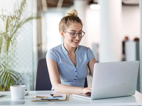 Eine Frau in einer kurzen Bluse sitzt an ihrem Schreibtisch und füllt das GLS-Schnellformular auf ihrem Laptop aus