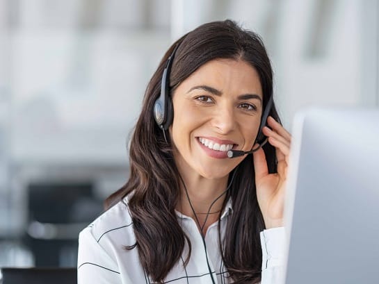 Eine GLS Call Center Mitarbeiterin mit Headset auf dem Kopf lächelt freundlich