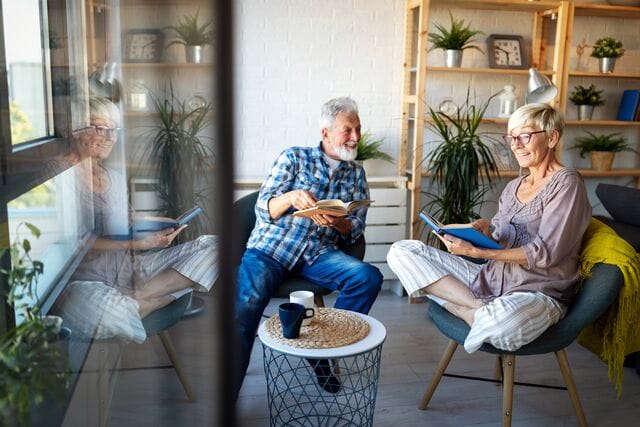 Älteres Ehepaar freut sich über die Brennholz-Paketzustellung und hat es gemütlich warm