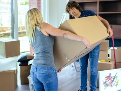 Pärchen hat ein großes Paket erhalten und trägt es gemeinsam