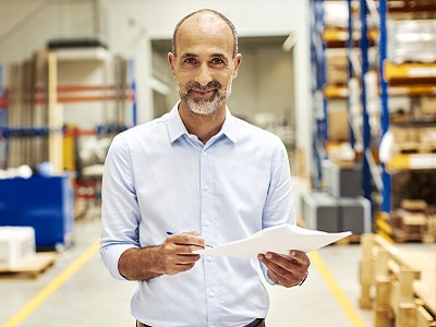 Versender im Lager mit Gefahrgutdokumenten in der Hand