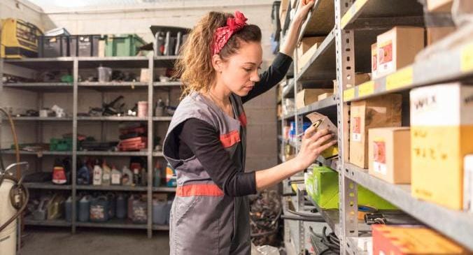 Woman standing in a warehouse looking for the right electrical part