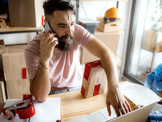 A man is on the phone and at the same time processing a GLS return on the laptop